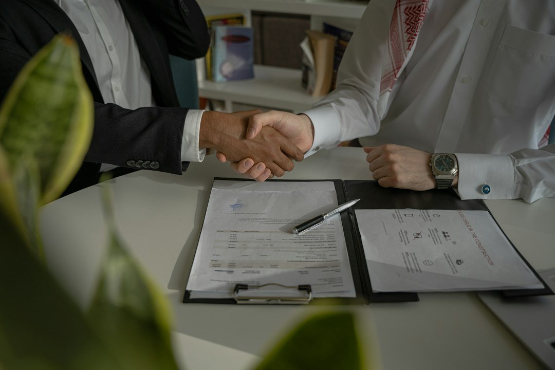 Two people shaking hands over a piece of paper, representing agreeing scope and terms in writing with a new vendor